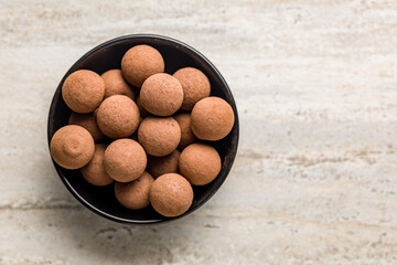 Chocolate truffles with cocoa powder in bowl on kitchen table. Top view.