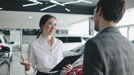 Sales representative discusses features and financing options with a potential buyer at a modern car dealership showroom