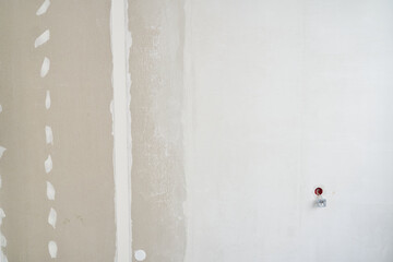 The wall is partially plastered, made of drywall. Preparing to install the outlet. Background with...