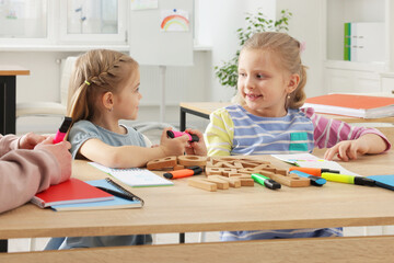 Fototapeta premium Children learning letters with teacher at desk indoors