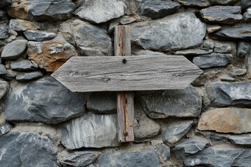 A wooden directional sign attached to a rugged stone wall