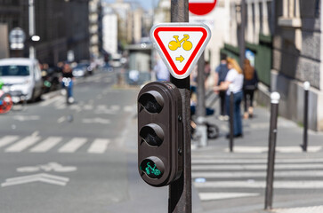 Gros plan sur un feu vert pour vélo dans la rue. Au dessus, un panneau vélo.