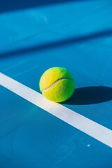 Pelota de tenis amarilla sobre cancha azul con líneas blancas bajo luz solar