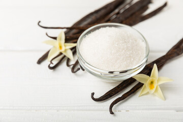 Fototapeta premium Aromatic vanilla sugar. Vanilla pods. Vanilla sticks, brown and white sugar in a bowl on a textured background. Vanilla flowers, spices and herbs for desserts and baking. Space for text. Copy space
