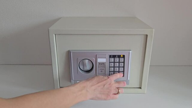 girl uses room safe to store money. entering electronic code to open