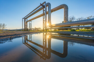 Geothermal energy. Pipelines and reflection at sunset in Larderello, Tuscany region, Italy