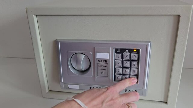 girl uses room safe to store money. entering electronic code to open