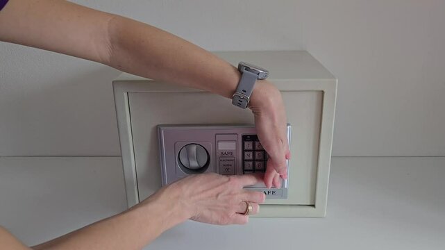 girl uses room safe to store money. entering electronic code to open