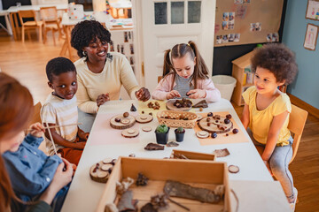 Curious preschool children explore nature objects with a teacher during a hands-on science activity...