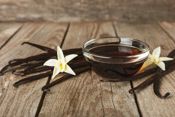 Vanilla extract in glassware on a wooden table. Vanilla extract for baking and desserts. Aromatic Homemade Vanilla Extract. Close -up. Place for the text. Copy space.