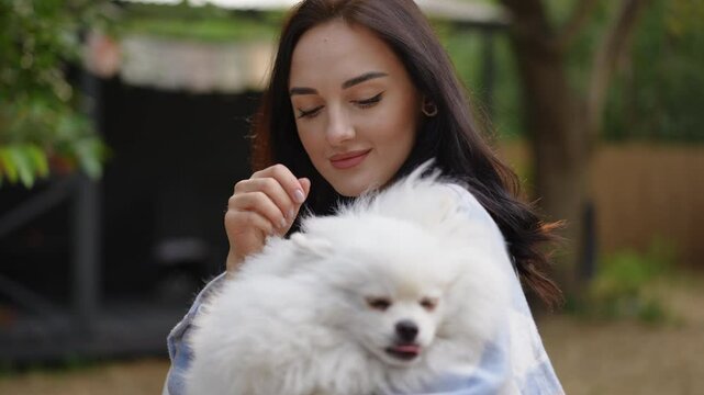 A woman gently and tenderly holds a fluffy Pomsky dog in a peaceful, serene outdoor environment, radiating pure joy
