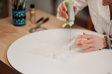 Designer pouring green paint into silicone mold for epoxy resin art