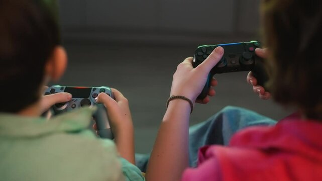 Tight shot of a mother and her son holding game controllers. Both are focused and enjoying their time together in a soft-lit room.