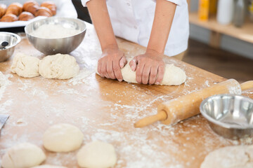 Chef working with dough in a bakery, surrounded by flour and bread-making tools, creating artisanal bread.