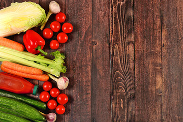 Healthy vegan products for healthy lifestyle. Tomatoes, cucumbers, carrots, peppers, broccoli, cabbage, celery and natural juice on wooden background, detox diet and weight loss concept