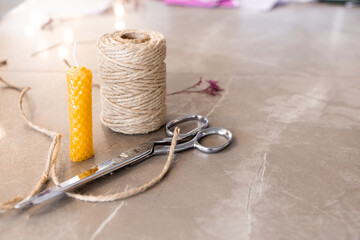 Crafting essentials. Twine, scissors, wax candle on marble surface