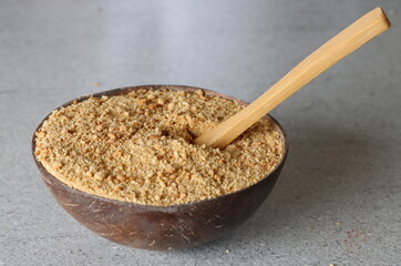 Ground biscuit and wooden spoon in a coconut bowl