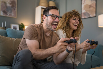 couple man and woman husband wife play console video games at home