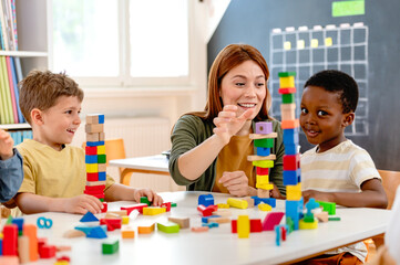 A teacher and diverse group of children build with colorful blocks in a classroom, promoting...