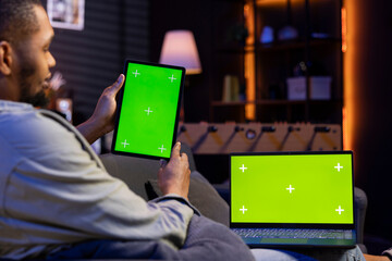 African american remote worker uses chroma key screen on gadget to work in the living room, sitting...