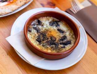 Delicious browned baked provolone cheese with champignon mushrooms served in clay bowl. Italian style cuisine