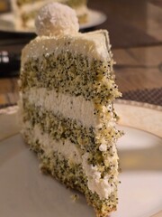 A tempting slice of cake features alternating layers of light green, poppy seed-speckled sponge and...