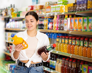 Young woman looking to buy tasty juice in supermarket