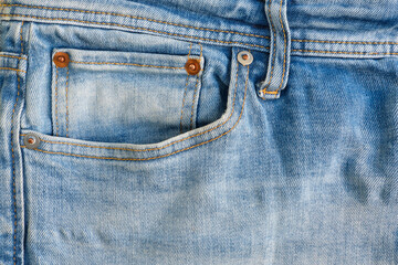 Closeup of a small watch pocket with copper rivets of a worn blue denim jeans trousers	