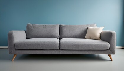 Fototapeta premium 淡いブルーのマット背景に、ふわっとしたクッションが特徴的な柔らかなグレーのソファが1つ置かれ、落ち着いた温かみのある空間が広がる
