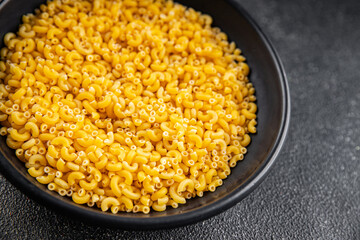 Macaroni pasta raw coquillette appetizer dish organic product fresh tasty gourmet food background on the table rustic food top view copy space