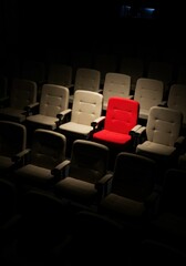 Obraz premium Spotlight on Single Red Chair in Empty Theater