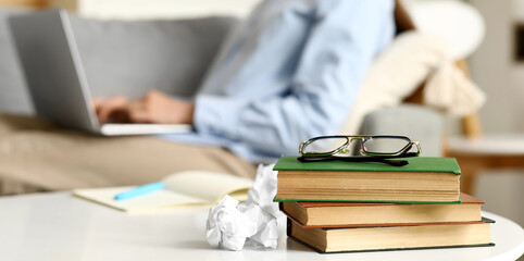 Beautiful female writer with laptop, notebook and books on  table, closeup