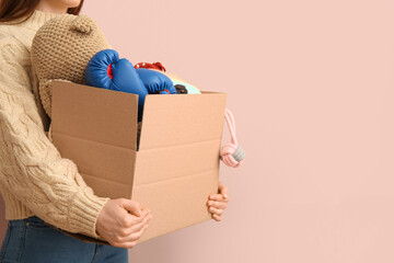 Woman holding box of unwanted stuff for yard sale on beige background