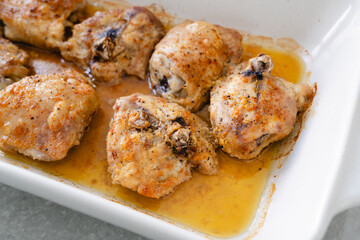  Close-up of juicy, golden-brown baked chicken thighs resting in flavorful juices.