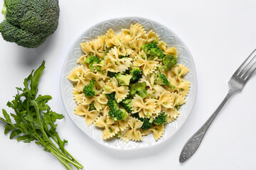 Plate of tasty pasta with broccoli on white background