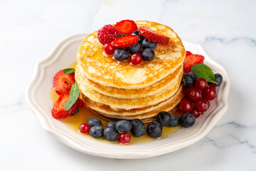 Healthy summer breakfast, homemade classic american pancakes with fresh fruit and honey, morning light gray stone background copy space top view