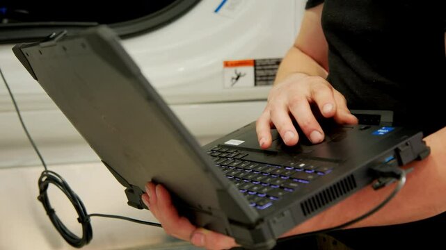 Professional truck mechanic using a laptop for vehicle diagnostics in a service garage.