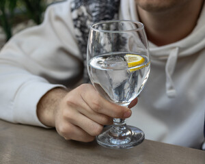 Person holding a refreshing glass of water with lemon