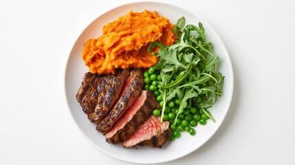Grilled steak with mashed sweet potatoes, peas, and arugula on a white plate.