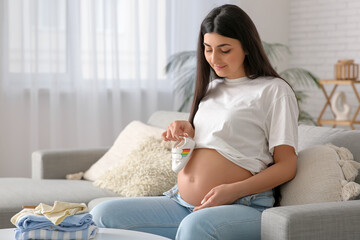 Beautiful pregnant woman with rattle at home