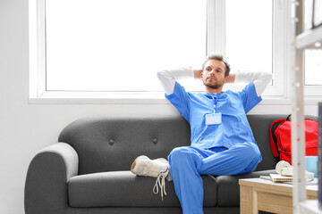 Male medical intern resting on sofa in library