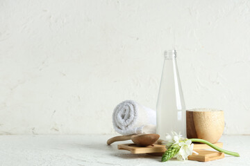 Bottle of natural rice water, grains, flower and clean towel on light background