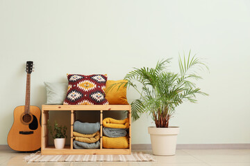 Interior of room with folded blankets, guitar and palm tree