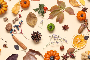 Candles in shape of pumpkin, autumn leaves and berries on beige background
