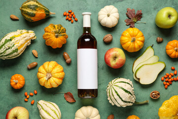 Bottle of wine with fruits and pumpkins on green grunge background