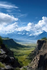 A panoramic perspective reveals a vibrant valley that descends into a rugged canyon, with steep cliffs soaring dramatically against a backdrop of expansive mountains capped with snow, all beneath a s