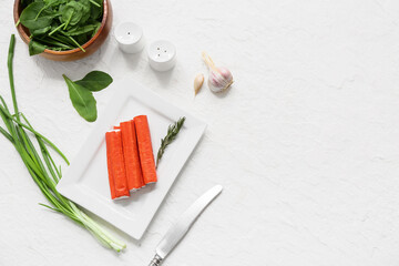 Plate with tasty crab sticks, spinach leaves and green onion on white background © Pixel-Shot