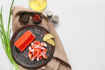 Plate with tasty crab sticks, slices of lemon and green onion on grey background © Pixel-Shot