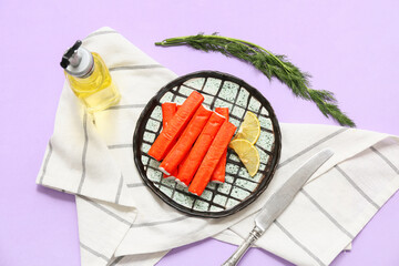 Plate with tasty crab sticks, slices of lemon and dill on lilac background © Pixel-Shot
