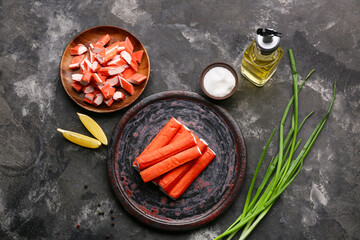 Plates with tasty crab sticks, pieces of lemon and green onion on black background © Pixel-Shot